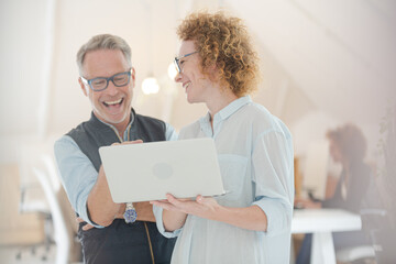 Portrait of man and woman with laptop, smiling in office