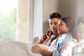 Teenage couple lying in bed and eating popcorn