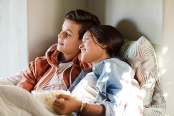 Teenage couple lying in bed and watching tv