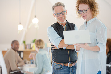 Portrait of man and woman with laptop, smiling in office