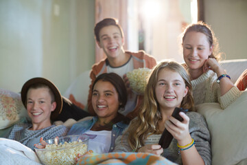Group of teenagers having fun while watching tv on sofa