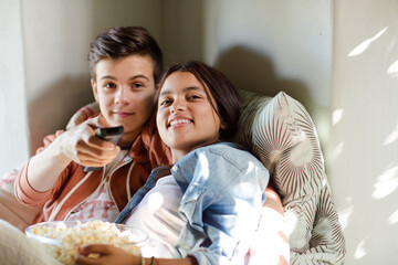 Teenage couple lying in bed and watching tv