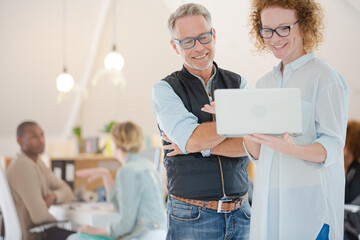 Portrait of man and woman with laptop, smiling in office