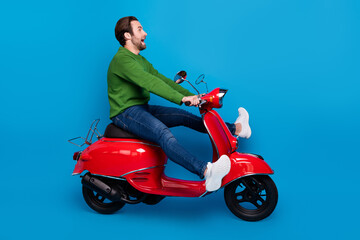 Fototapeta na wymiar Full size profile side photo of excited smiling male ride fast speed moped look copyspace isolated on blue color background