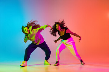 Two young stylish hip-hop dancers on colorful gradient background in neon lights