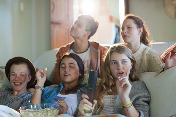 Group of teenagers having fun while watching tv on sofa