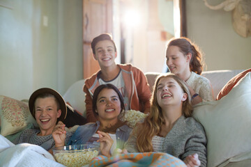 Group of teenagers having fun while watching tv on sofa