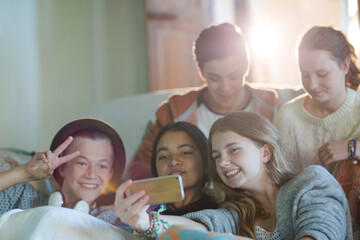 Group of teenagers taking selfie on sofa in living room