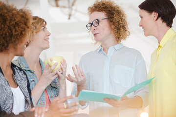 Women with coffe cup talking in office