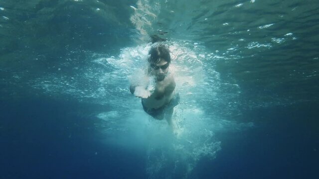 Ragazzo nuota nel mare in stile libero visto da sott'acqua
