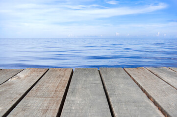 Fototapeta na wymiar Wooden floor or plank on sand beach in summer. For product display.Calm Sea and Blue Sky Background.