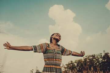 Fototapeta na wymiar Smiling woman with arms outstretched against sky