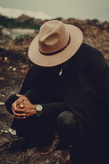 Man in hat crouching in landscape