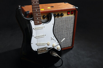 Fototapeta premium Tube amplifier for electric guitar with black guitar on black background.