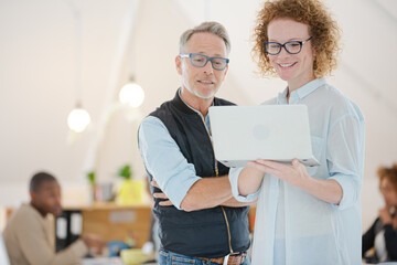 Portrait of man and woman with laptop, smiling in office