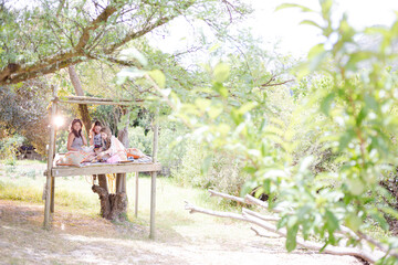 Naklejka premium Three teenage girls playing in tree house in summer