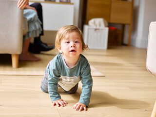 Baby boy crawling on floor in living room
