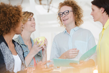 Women with coffe cup talking in office