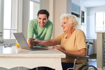Man helping senior woman on laptop computer with video call