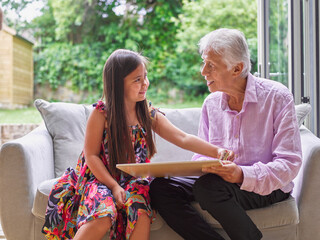 Grandfather playing with granddaughter on sofa