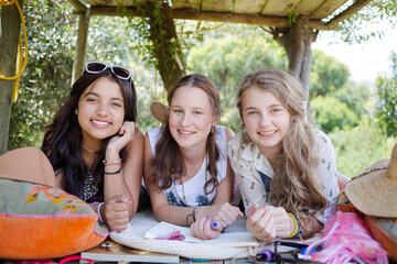 Three teenage girls reading magazine while lying in tree house in summer