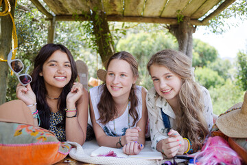 Three teenage girls reading magazine while lying in tree house in summer