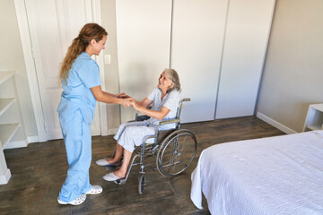 Nurse helps senior citizen in a wheelchair to get up