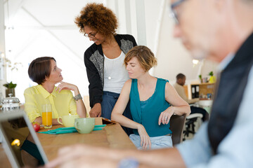 Women looking at digital tablet and smiling in office