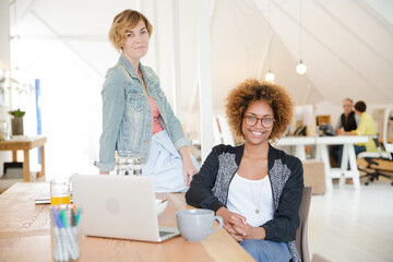 Obraz premium Portrait of women smiling in office with laptop on desk