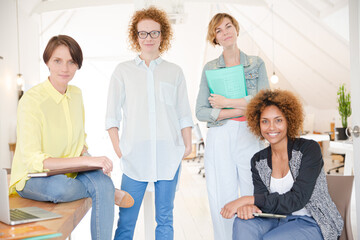 Portrait of women smiling in office with laptop on desk