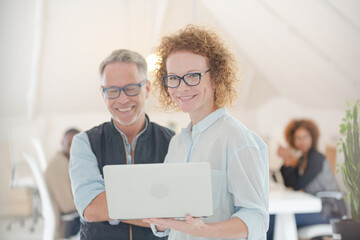 Fototapeta premium Portrait of man and woman with laptop, smiling in office