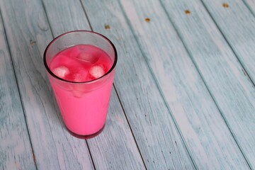 Iced rose syrup with milk on wooden table