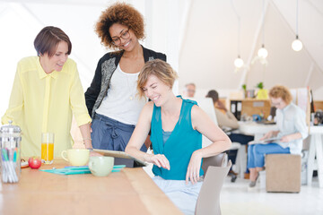 Women looking at digital tablet and smiling in office