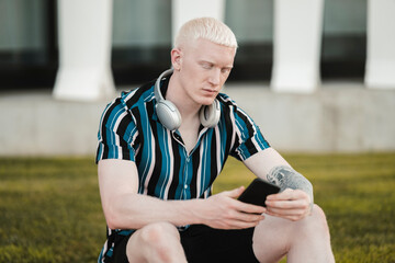 handsome young albino man using smartphone - Powered by Adobe