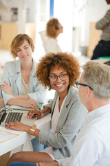 Fototapeta premium Three office workers talking at desk with laptop