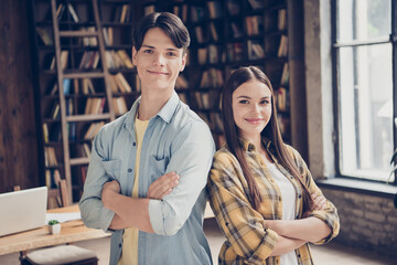 Portrait of two attractive cheerful content intellectual pupils folded arms at library loft...