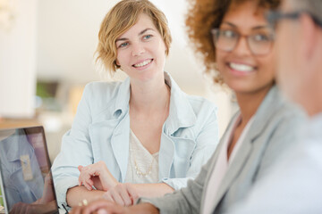 Fototapeta premium Three office workers talking at desk with laptop