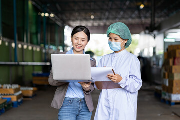 Group of Asian female employee worker wearing mask and hairnet using digital table checking product of Basil seed with fruit in beverage factory industry. Inspection quality control