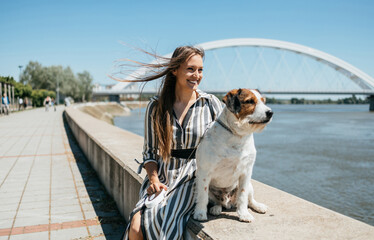 Beautiful young woman enjoying outdoors with her adorable adopted mixed breed dog. Bright sunny day.