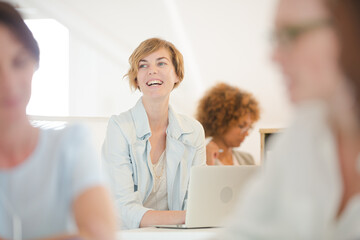 Obraz premium Portrait woman sitting at desk, using laptop smiling in office, colleagues