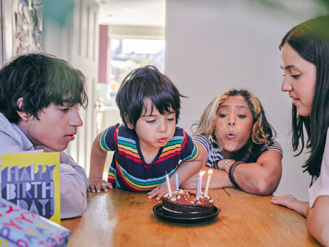 Family Blowing Out Candles On Birthday Cake