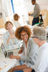 Obraz premium Three office workers talking at desk with laptop