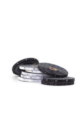 Professional tailor's equipment. Close-up of white and black reels with size tags from XXS to L lying on top of each other or sideways on white isolated background with space for text or design. 