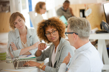Fototapeta premium Three office workers talking at desk with laptop