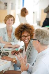 Obraz premium Three office workers talking at desk with laptop