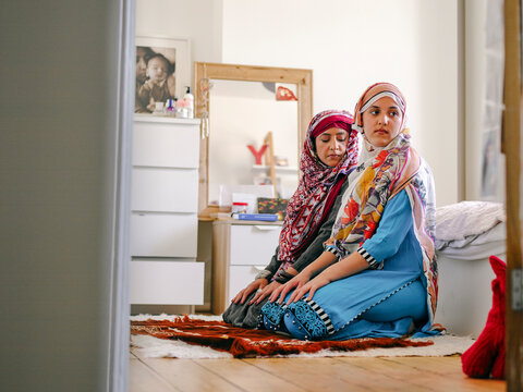 Muslim woman with teenage daughter praying at home