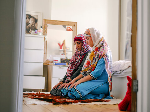 Muslim woman with teenage daughter praying at home