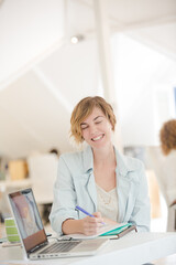 Portrait of woman sitting at desk with laptop in office