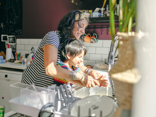 Mother and son washing hands in kitchen sink