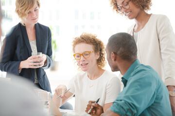 Office workers talking and smiling at meeting